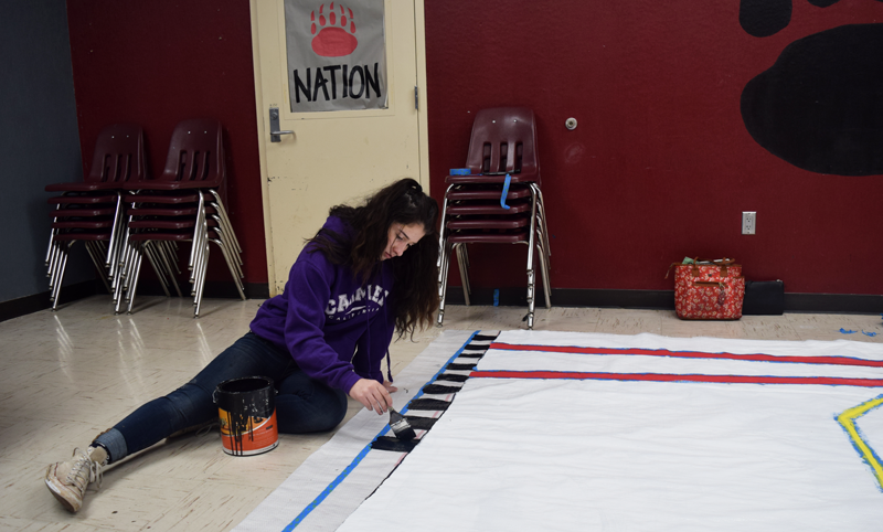 Junior Shelbi Beghetti paints a homecoming sign in the Student Store. Photo by Hope Chylewski