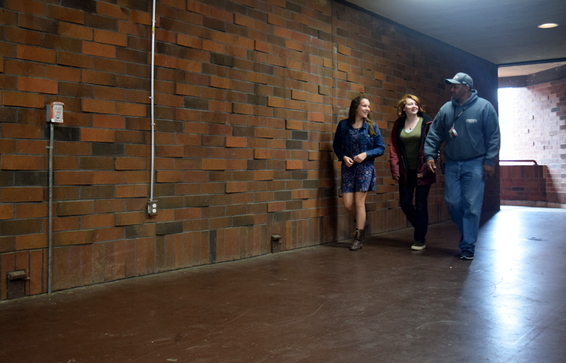 Freshman Emma Cutter, Sophomore Leo Jackson and Campus Supervisor Ralph Lewis stroll through the dark hallway in the upper floor of the A-wing at Bear River High School. The fire alarm in the foreground was recently pulled. Photo by Taylor Wohlgemuth