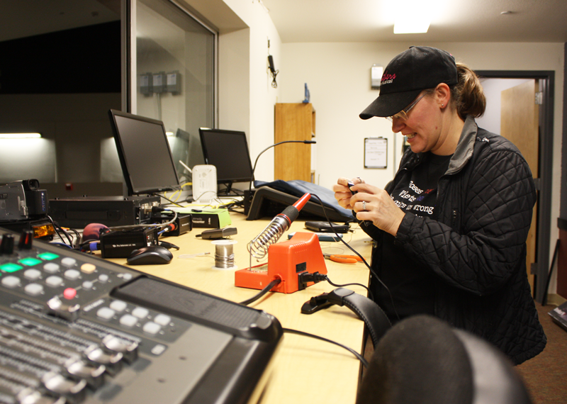 Theater Manager Erin Beatie solders a mic behind the scenes for a production. Photo by Bella Ferrari