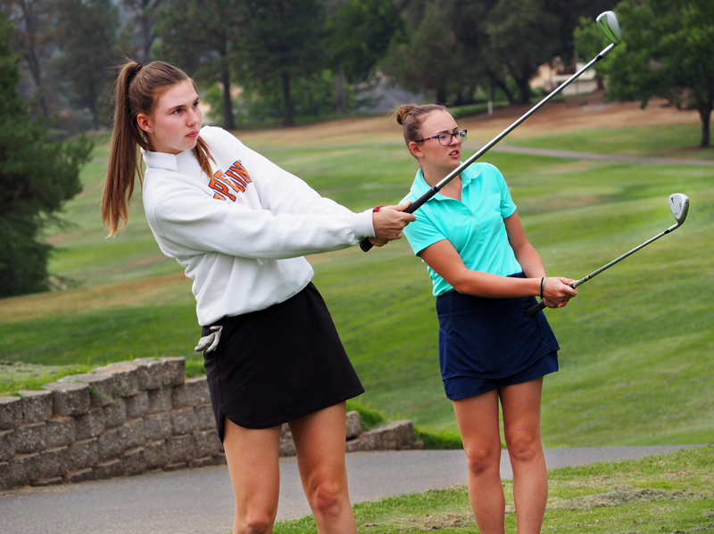 Junior Sarah Aanenson and Freshman Julia Pisenti chip on the practice green at LOP. Photo by Kalei Owen