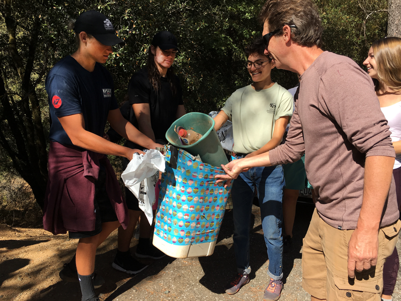 Key Club Supervisor Jeffrey Carrow picks up trash alongside Seniors Dylan Sinclair and Trae Nix during this years annual Yuba River Clean Up. Photo by Sonora Slater 