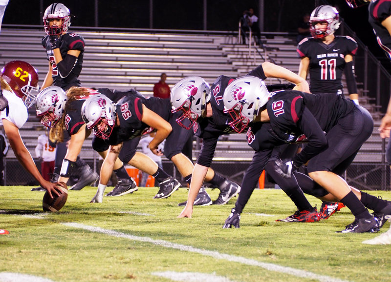 Varsity football players take a defensive stance against Encina at the Homecoming game. Photo by Kalei Owen