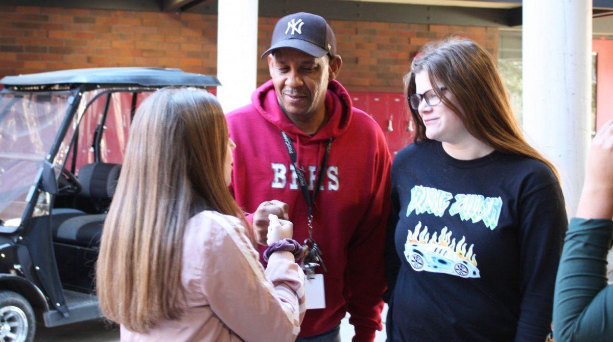 Campus Supervisor Ralph Lewis took every opportunity to interact with students, including the conversation with Seniors Hannah Weidler and River Jarman pictured here. Photo by Isaiah Williams