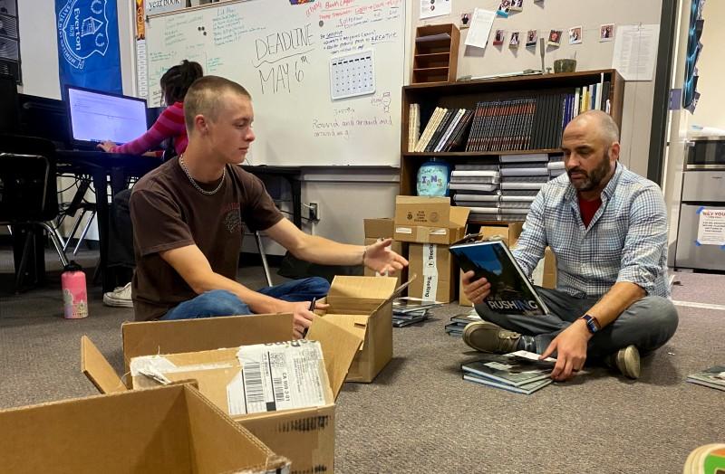 Derek Warner and Yearbook advisor Mike DeCicco sort yearbooks to get ready for distribution day. Photo by Sara Tate.